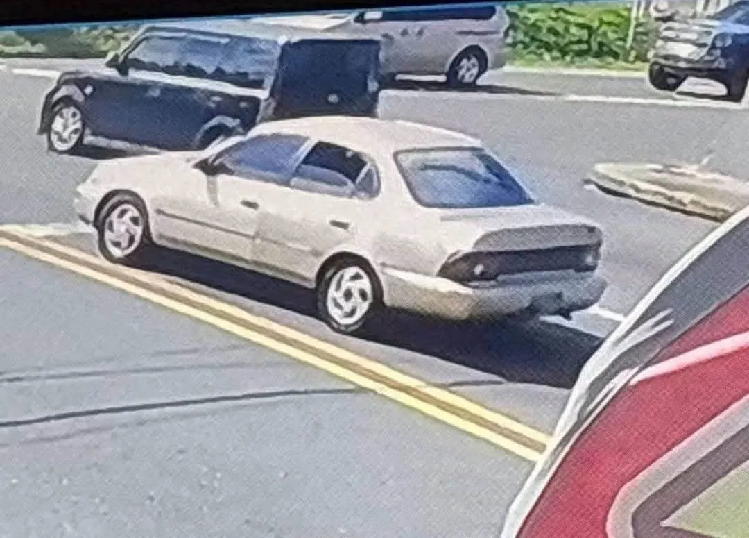 Un sedán color crema de cuatro puertas estacionado en un área comercial.
