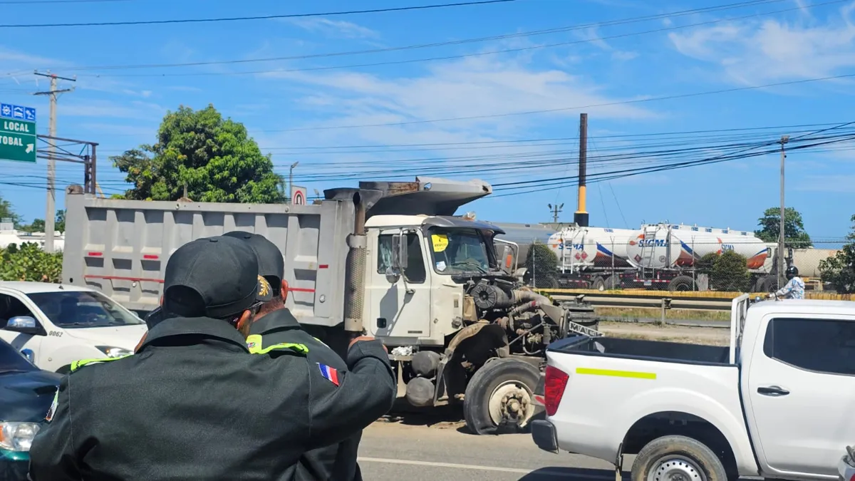 Camión volteo blanco con el frente destruido en la autopista 6 de Noviembre, observado por agentes de tránsito de espaldas en primer plano