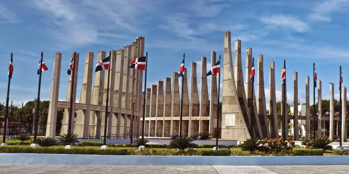 Monumento a los Constituyentes en San Cristóbal, con sus columnas de concreto y banderas dominicanas bajo un cielo azul