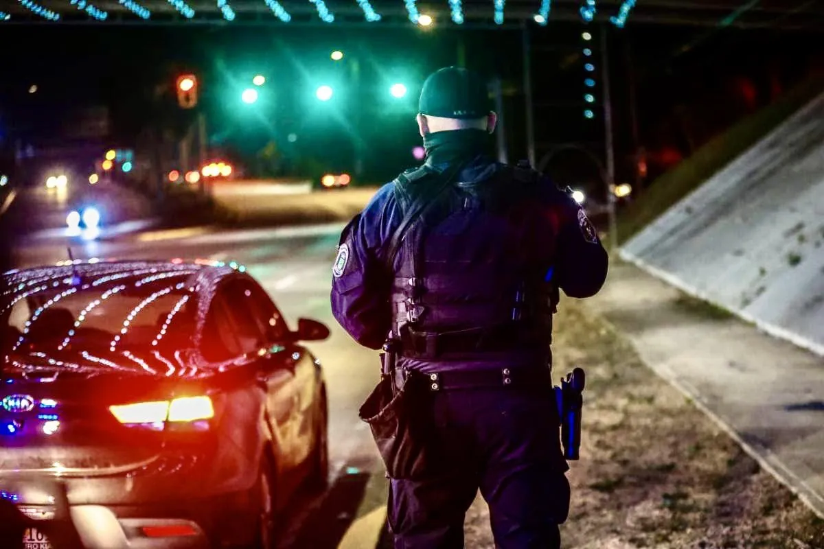 Un policía municipal de espaldas junto a una patrulla durante un operativo nocturno en una carretera de Puerto Rico