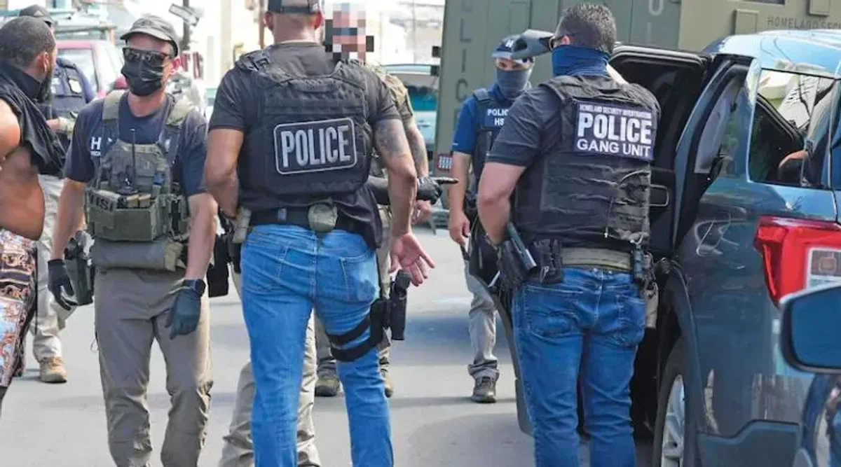 Agentes federales con chalecos que dicen Police caminan por una calle durante un operativo migratorio
