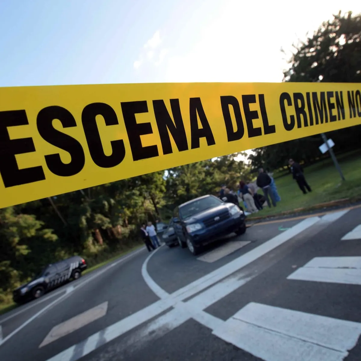 Cinta amarilla con la leyenda «Escena del crimen no pase» en una calle acordonada por la Policía, imagen de apoyo