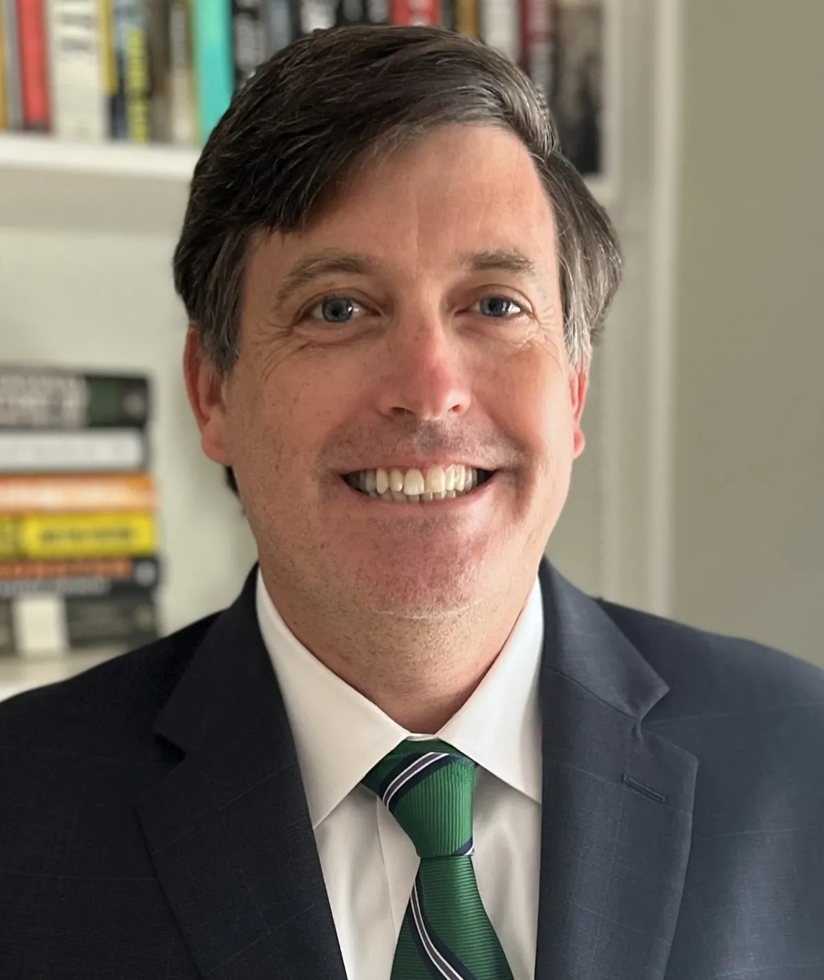 Retrato del juez federal Brendan Hurson, con traje oscuro y corbata verde, frente a una estantería con libros