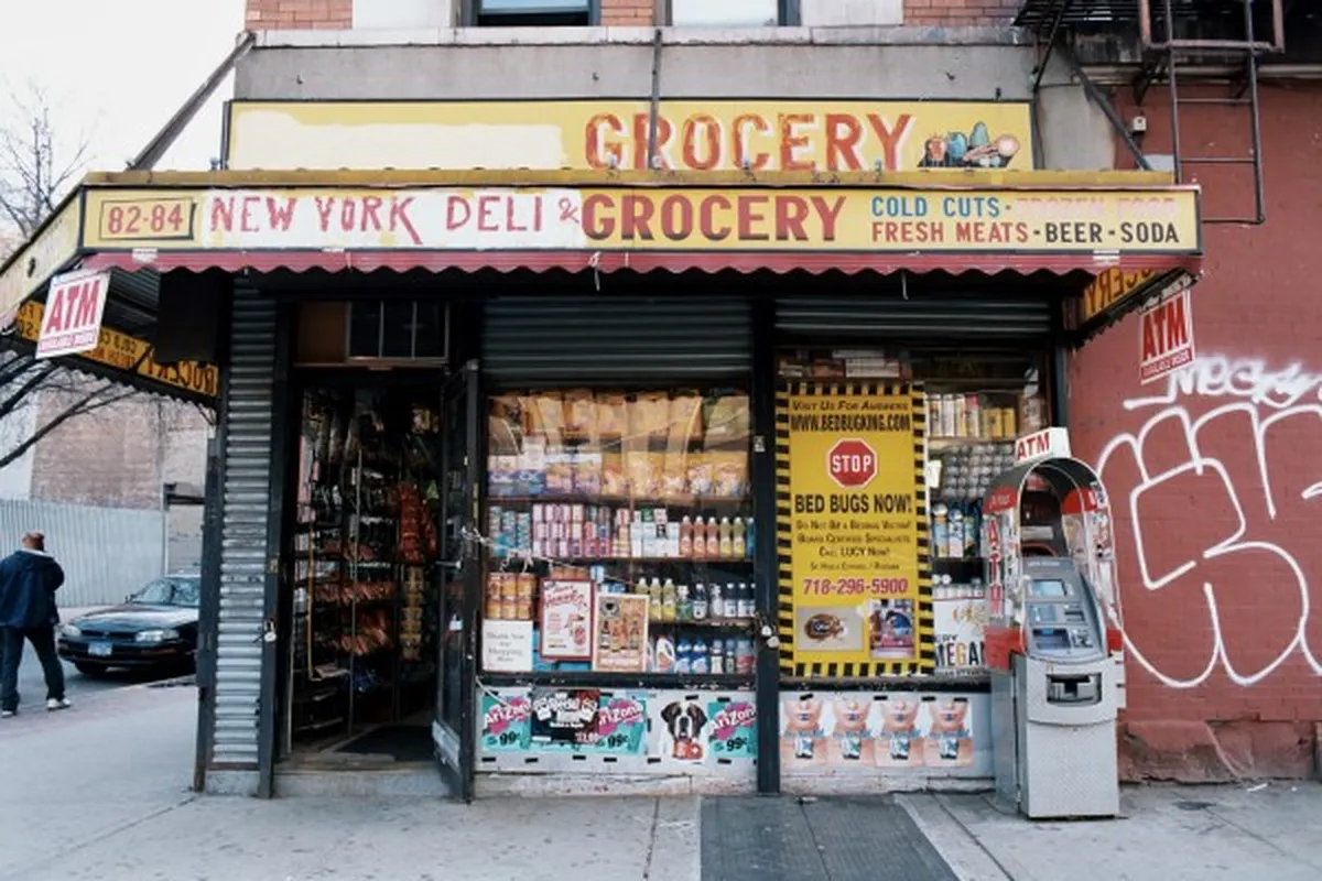 Fachada de una bodega y deli de Nueva York con rótulos de grocery y productos en la vitrina, imagen de apoyo