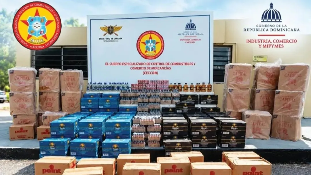 Cajas, botellas y paquetes de cigarrillos y bebidas alcohólicas incautadas, expuestos frente al letrero institucional del CECCOM