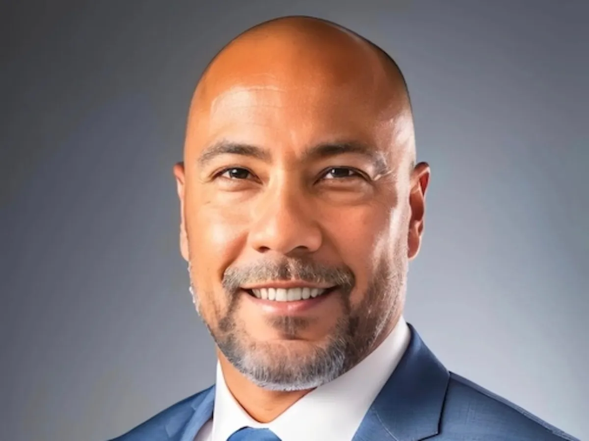 Retrato de Tony Sabio, candidato al Congreso por Virginia, con traje azul y corbata sobre un fondo gris
