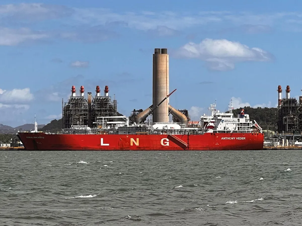 Un buque rojo de gas natural licuado con las letras LNG atracado frente a la central eléctrica de San Juan, en la bahía