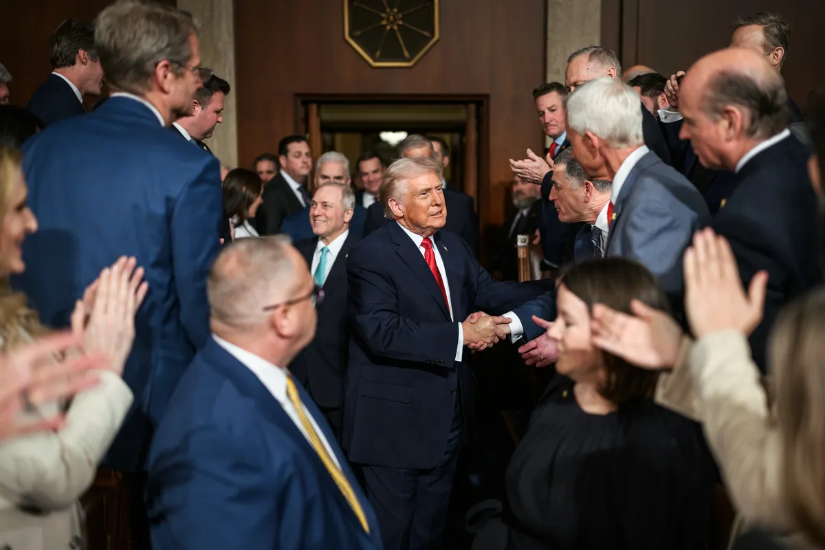 Donald Trump saluda y estrecha manos con simpatizantes en un pasillo rodeado de funcionarios y seguidores